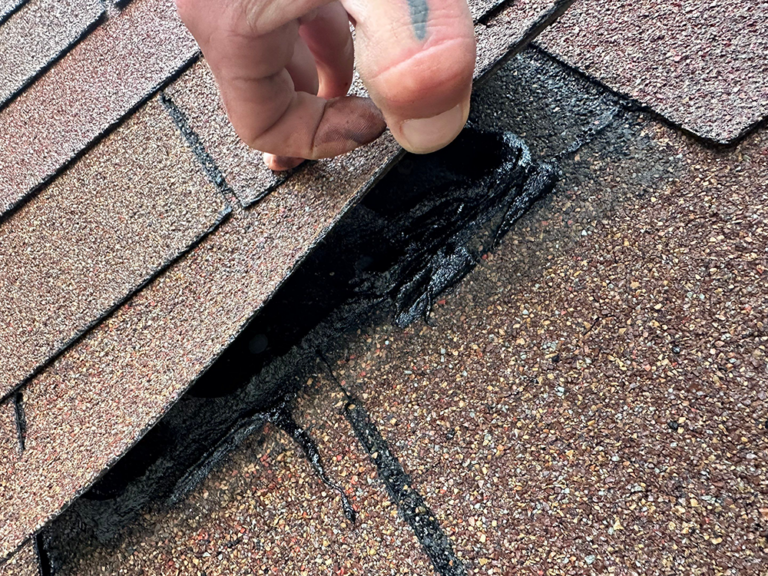 Photo: AR Remodeling pulling up loose shingle during roof inspection
